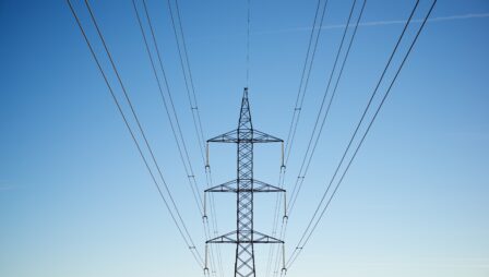 Voimalinjapylväs ja voimalinjat sinistä taivasta vasten.