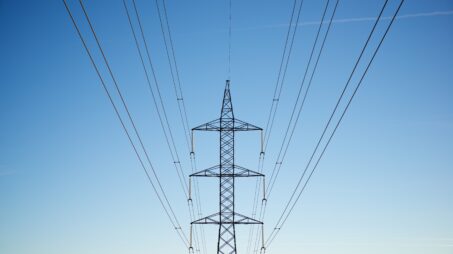 Voimalinjapylväs ja voimalinjat sinistä taivasta vasten.